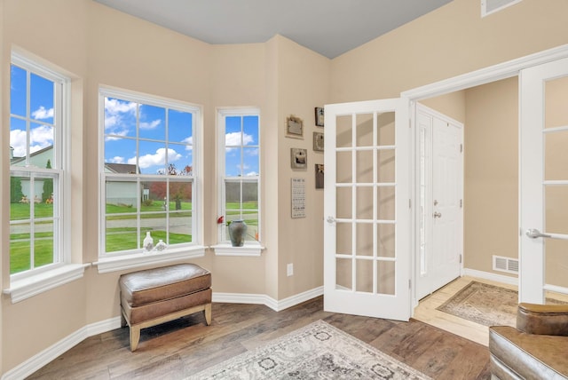 unfurnished room with hardwood / wood-style floors, plenty of natural light, and french doors