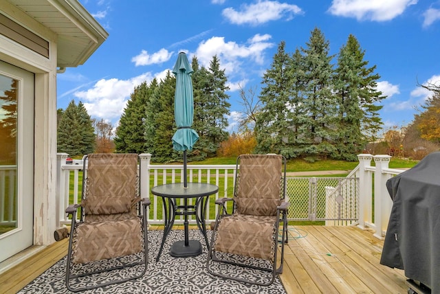 wooden deck with a yard and a grill