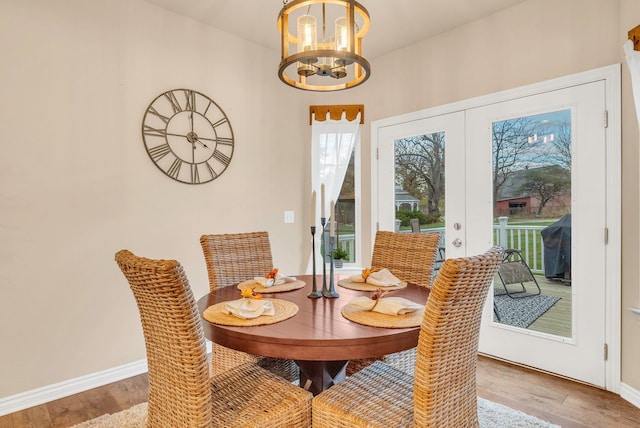 dining room with light hardwood / wood-style floors, french doors, and an inviting chandelier