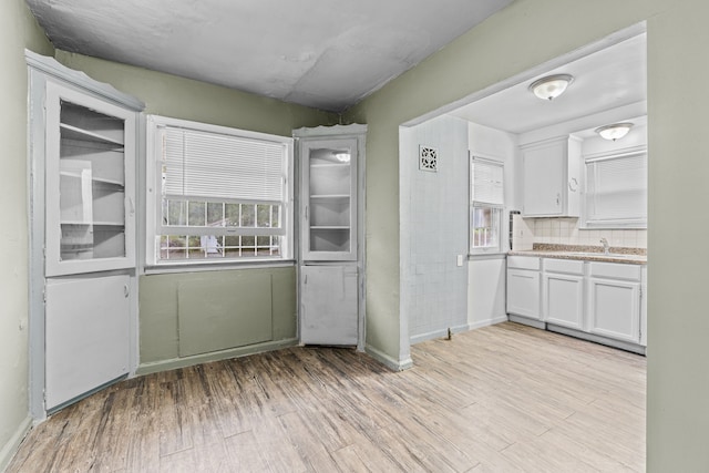 kitchen with decorative backsplash, light hardwood / wood-style floors, and white cabinetry