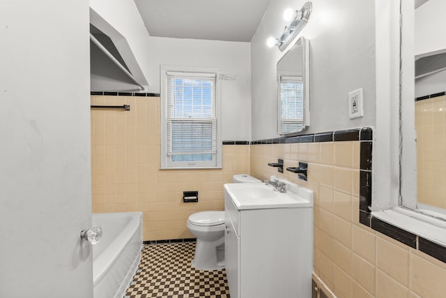 bathroom featuring a washtub, vanity, toilet, and tile walls