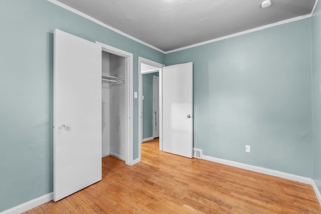 unfurnished bedroom featuring crown molding, a closet, and light hardwood / wood-style floors