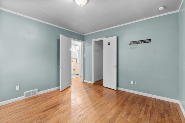 empty room with light wood-type flooring and crown molding