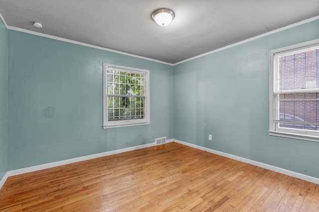 spare room featuring a healthy amount of sunlight, light hardwood / wood-style floors, and crown molding