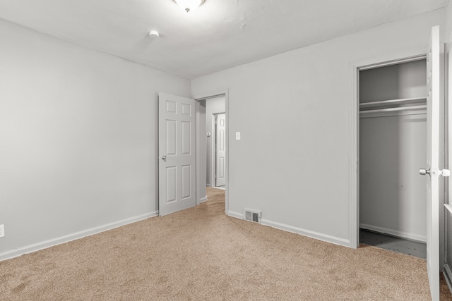 unfurnished bedroom with a closet and light colored carpet