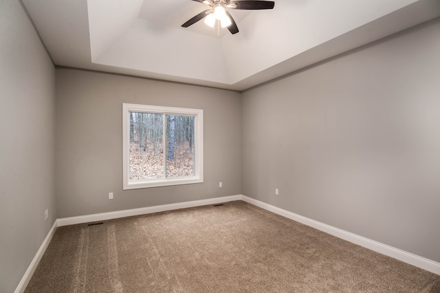 carpeted spare room featuring ceiling fan and a tray ceiling