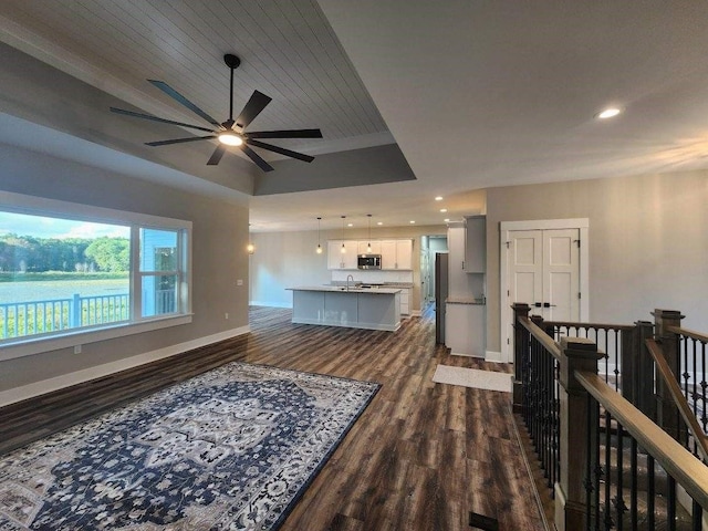 living room featuring ceiling fan, sink, dark wood-type flooring, a raised ceiling, and wood ceiling