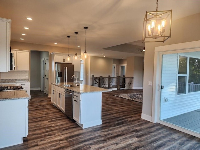 kitchen featuring white cabinets, decorative light fixtures, stainless steel appliances, and a center island with sink