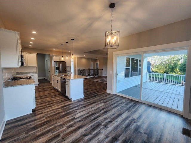 kitchen featuring white cabinetry, dark hardwood / wood-style flooring, an island with sink, pendant lighting, and appliances with stainless steel finishes