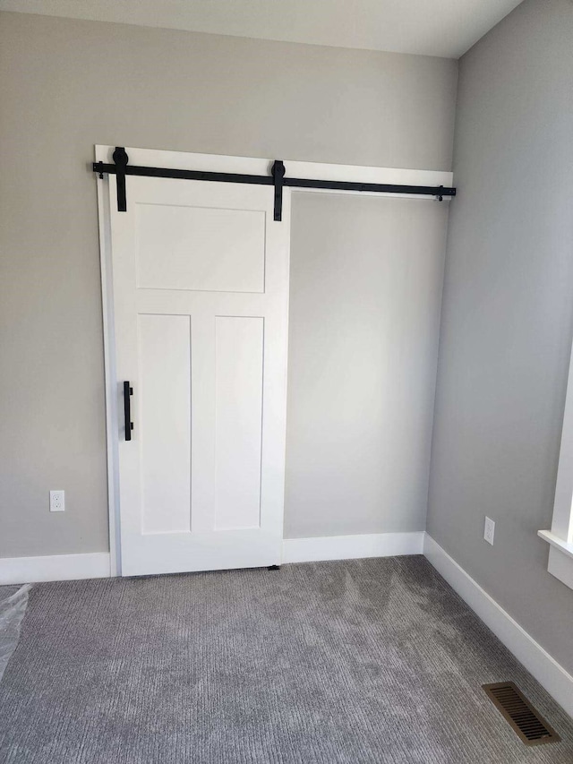 unfurnished bedroom featuring carpet and a barn door