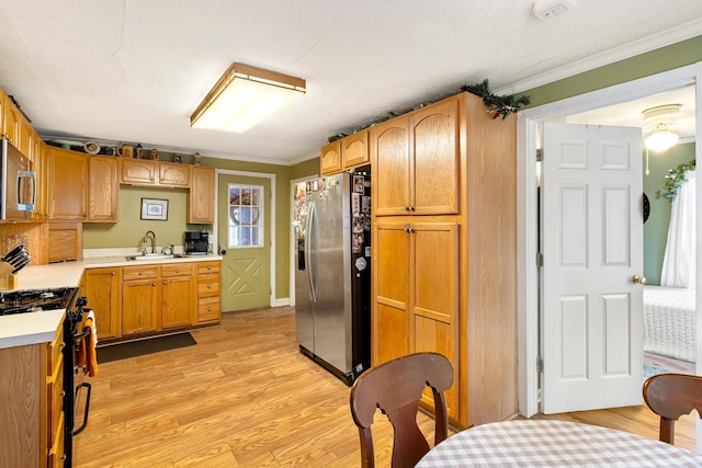 kitchen with crown molding, sink, light hardwood / wood-style floors, and appliances with stainless steel finishes