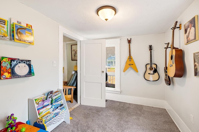 recreation room featuring carpet and a textured ceiling