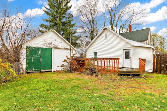 rear view of property with a yard, a deck, and an outdoor structure