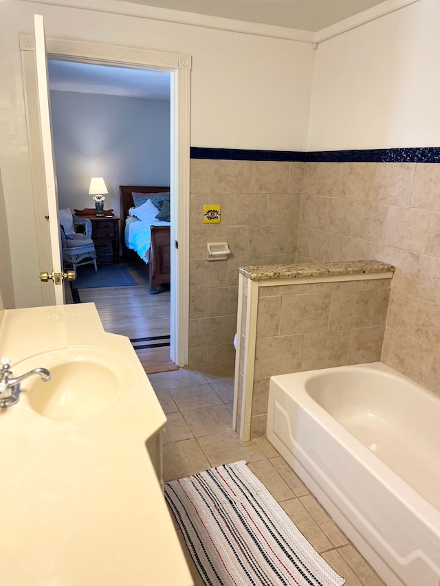 bathroom with tile patterned floors, tile walls, a bathing tub, and sink