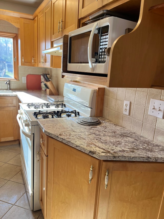 kitchen featuring light stone counters, white gas range, sink, and tasteful backsplash