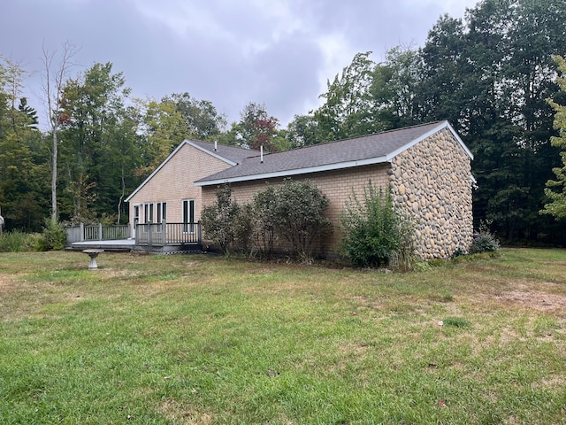 view of side of property featuring a lawn and a wooden deck