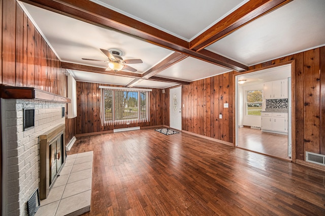 unfurnished living room featuring wooden walls, light hardwood / wood-style floors, and a wealth of natural light