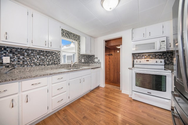 kitchen featuring tasteful backsplash, light stone counters, light hardwood / wood-style flooring, white appliances, and white cabinets