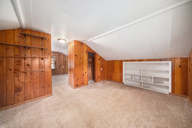 additional living space featuring lofted ceiling, light colored carpet, and wooden walls