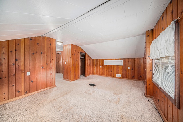 bonus room featuring wooden walls, light carpet, and vaulted ceiling