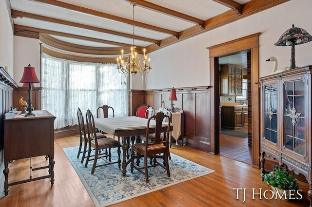 dining space featuring beamed ceiling, light hardwood / wood-style flooring, and a notable chandelier