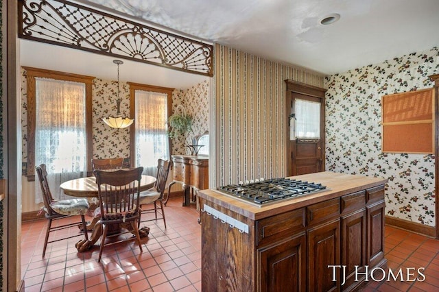 kitchen with wood counters, tile patterned floors, hanging light fixtures, and stainless steel gas stovetop