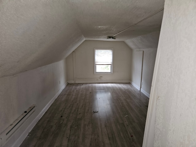 bonus room featuring a textured ceiling, dark hardwood / wood-style flooring, lofted ceiling, and baseboard heating