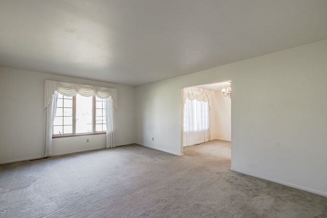 empty room featuring light carpet and an inviting chandelier