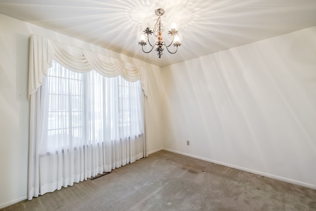 empty room with carpet floors and an inviting chandelier