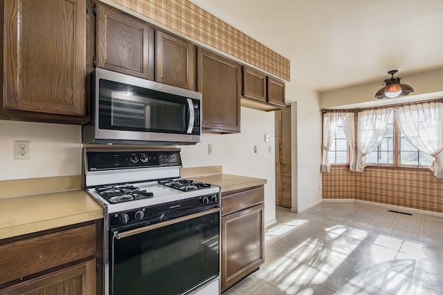 kitchen featuring dark brown cabinets, light tile patterned floors, and white range with gas cooktop