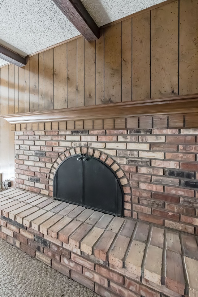 room details featuring carpet flooring, beam ceiling, a textured ceiling, and wood walls