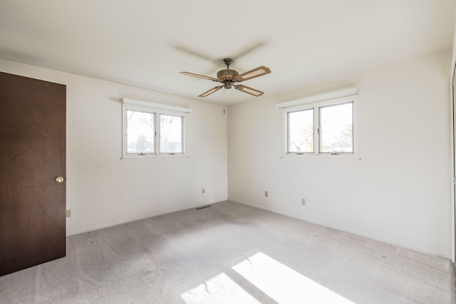 carpeted empty room with ceiling fan and a healthy amount of sunlight