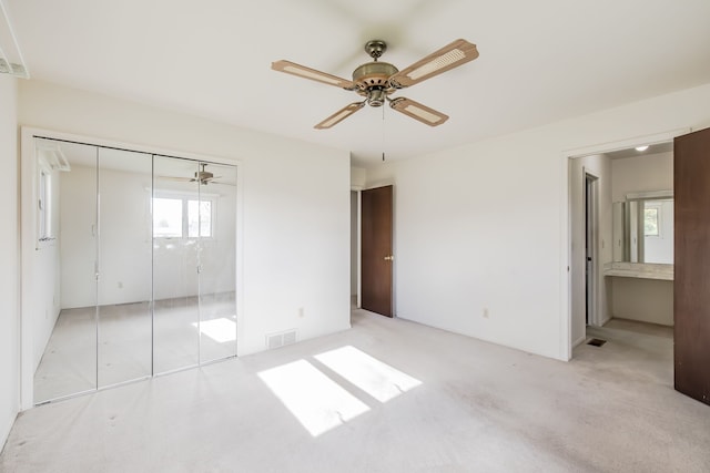 unfurnished bedroom featuring ensuite bath, ceiling fan, a closet, and light carpet