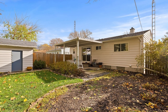 back of house with a patio, a chimney, fence, a yard, and an outdoor structure