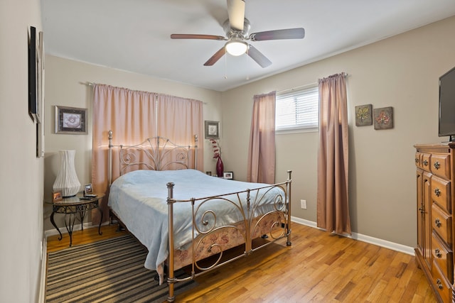 bedroom featuring light wood finished floors, baseboards, and a ceiling fan