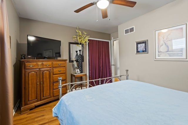 bedroom featuring a ceiling fan, visible vents, and light wood-style flooring