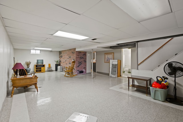 basement featuring a paneled ceiling, baseboards, stairway, and tile patterned floors