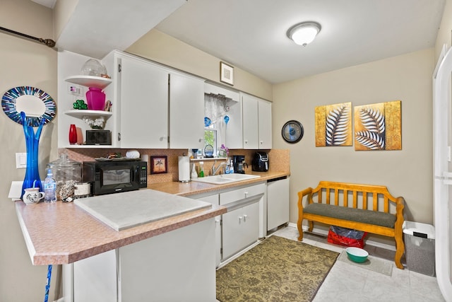 kitchen with a sink, black microwave, white cabinets, and dishwasher