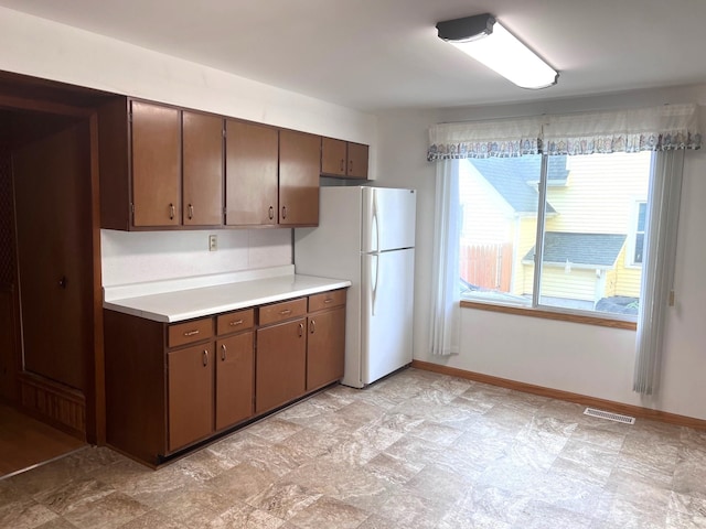 kitchen with white fridge and dark brown cabinetry