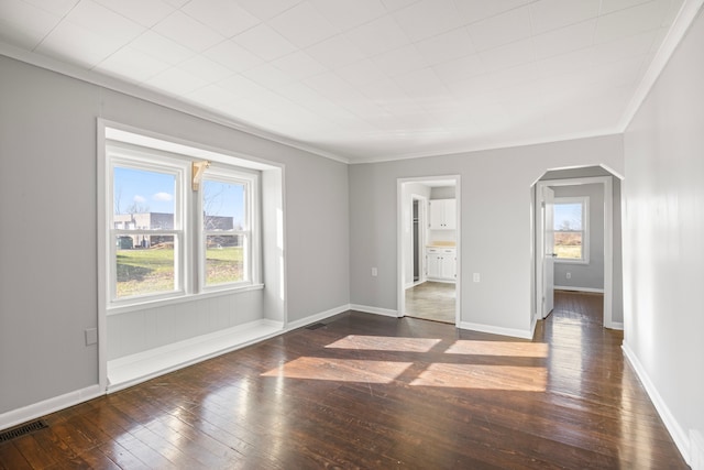 spare room with dark hardwood / wood-style flooring, a wealth of natural light, and crown molding