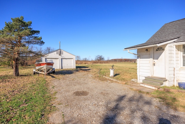 view of yard with a rural view, a garage, and an outbuilding