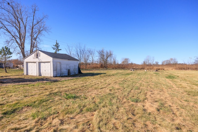 view of yard featuring a rural view, a garage, and an outdoor structure