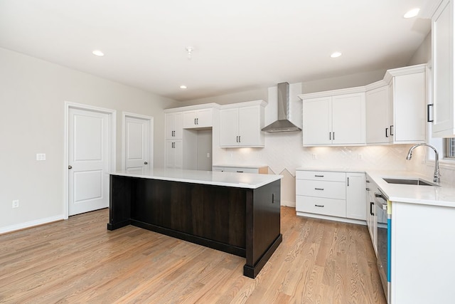 kitchen with white cabinetry, sink, wall chimney exhaust hood, and a kitchen island