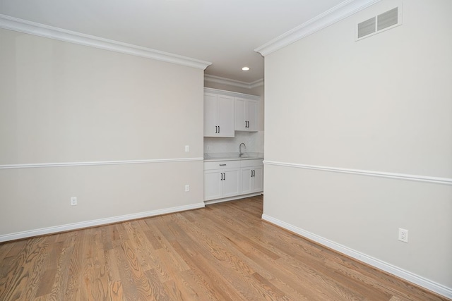 spare room with light hardwood / wood-style flooring, ornamental molding, and sink