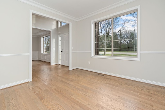 spare room with light hardwood / wood-style flooring, plenty of natural light, and crown molding