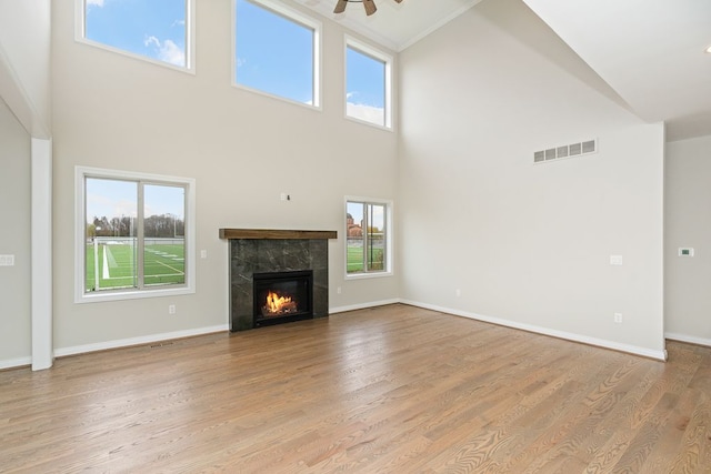 unfurnished living room featuring a fireplace, light wood-type flooring, high vaulted ceiling, and ceiling fan