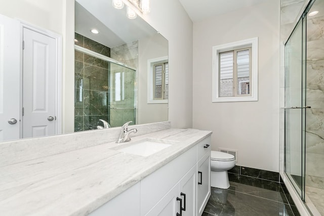 bathroom featuring vanity, toilet, and a shower with shower door