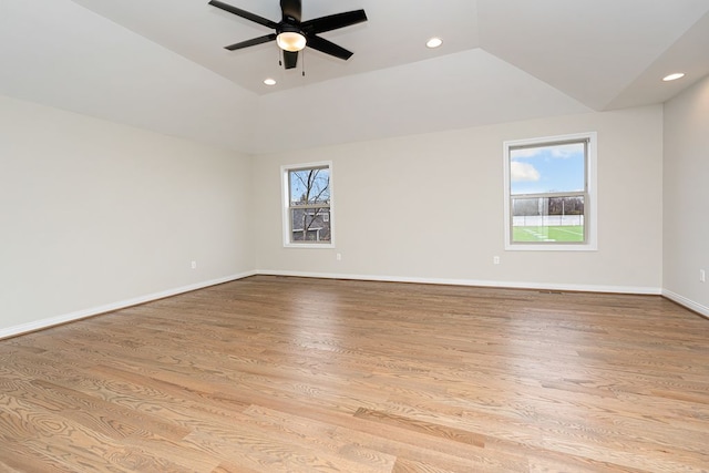 empty room with ceiling fan, a healthy amount of sunlight, vaulted ceiling, and light wood-type flooring