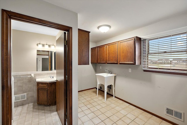 laundry area featuring sink and light tile patterned flooring