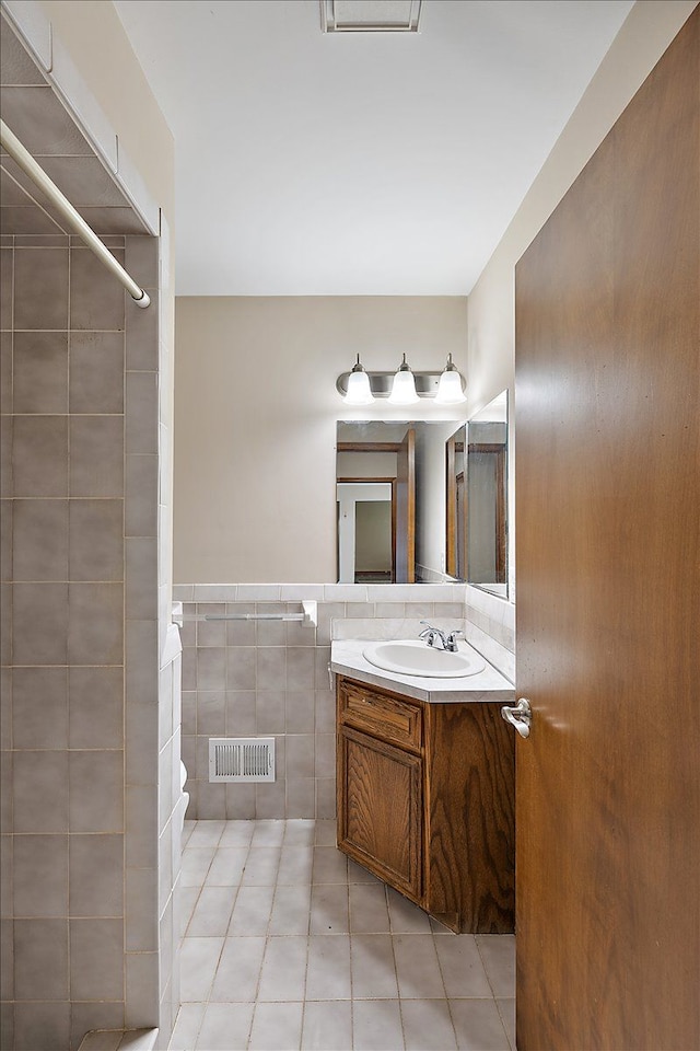 bathroom with tile patterned floors, vanity, tile walls, and walk in shower